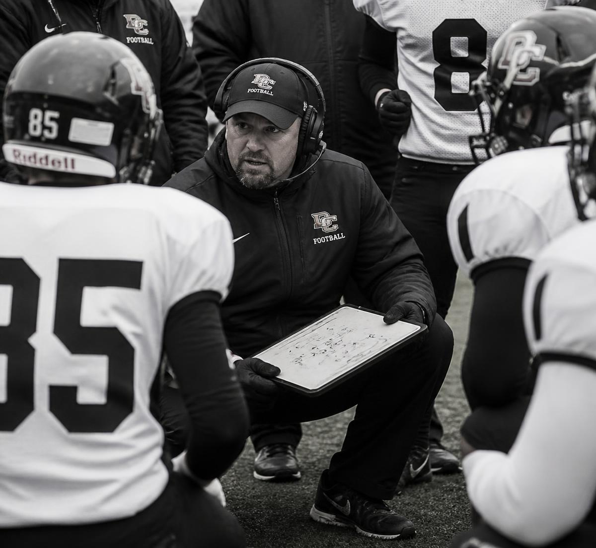 Football coach with a play board talking to his players on the sideline